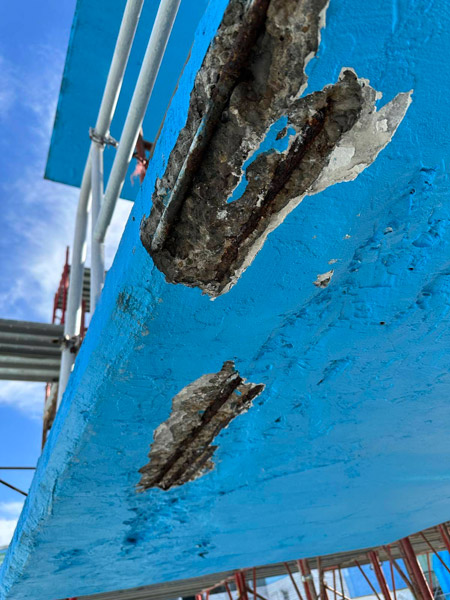 Damaged concrete structure of a diving tower with exposed and corroded reinforcement.