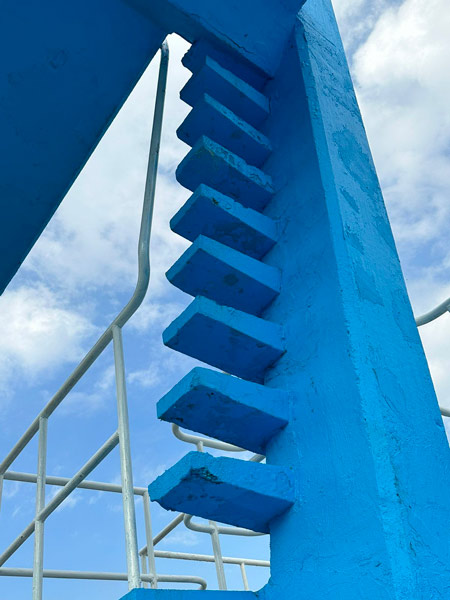 Crumbling sections and cracked surfaces of the concrete diving tower before restoration.